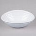 A white oblong melamine bowl with a swirl pattern on a white surface.