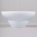 A close-up of an Elite Global Solutions white melamine bowl with a small rim on a gray surface.