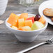 A white Elite Global Solutions melamine bowl filled with fruit on a table.