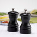Two black Chef Specialties Capstan ebony pepper mills on a table.