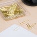 A box of Acco gold paper clips on a table.