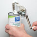 A hand using a Choice wall mount can opener to open a can of sweet corn.