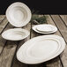 An Elite Global Solutions off white melamine stoneware oval serving dish on a wood table