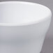 A close-up of a white Elite Global Solutions round melamine bowl with a small rim.