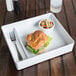 A white melamine tray with a sandwich and pasta in it.