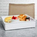 A white melamine tray with food including strawberries and a banana on a table.