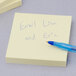 A 3M Canary Yellow Post-It note pad with a blue pen on it.
