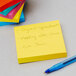 A stack of yellow Post-It notes with a blue pen next to it.