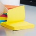 A hand holding a yellow 3M Post-It note pad.