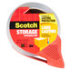 A roll of 3M Scotch clear packaging tape with a red label and a red tape dispenser.