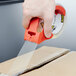 A hand uses a 3M Scotch tape dispenser to seal a box.