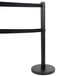 A black metal Aarco crowd control stanchion with dual black ribbons.