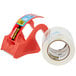 A roll of clear 3M Scotch heavy-duty packaging tape with a red dispenser with a red handle.