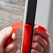 A person's hands using 3M Scotch black mounting tape to hang a red piece of paper on a wooden door.