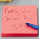A close-up of a 3M Canary Yellow and Neon Color Assorted Post-It note with a pen on it.
