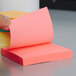 A hand holding a stack of yellow and pink Post-It notes.