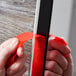 A person's hands using 3M Scotch black mounting tape to hang red tape on a wooden door.