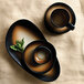A table set with black and brown Tiger Organic porcelain bowls and cups.