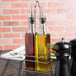 A Choice oil and vinegar cruet set on a table in a metal rack.