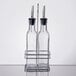 A metal rack holding two clear glass oil and vinegar bottles with metal spouts.