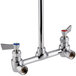 A Fisher wall mounted chrome pre-rinse faucet with two handles and two valves.