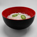A black and red Elite Global Solutions two-tone melamine bowl filled with noodles and jalapenos.