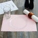 A pink Hoffmaster paper placemat with a scalloped edge under a plate and glass.