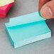 A person holding a blue 3M Post-It note.