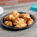 A table with a Fineline black plastic catering tray holding croissants.