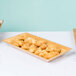 An American Metalcraft rectangular bamboo tray with croissants on a table.