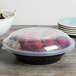 A Fineline black plastic catering bowl filled with strawberries on a table.