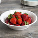 A white Fineline Low Profile Plastic Catering Bowl filled with strawberries on a table.