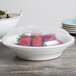 A white Fineline low profile plastic catering bowl filled with strawberries on a table.