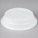 A white plastic low profile bowl by Fineline on a gray surface.