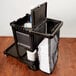 A black Rubbermaid cleaning cart with a black mesh bag full of white towels.