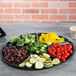 A black Fineline plastic catering tray with 6 compartments holding vegetables.