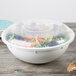 A clear Fineline plastic catering bowl lid on a clear bowl filled with salad.
