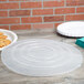 A clear plastic Fineline catering bowl lid on a stack of white plates with cookies.