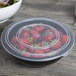 A Fineline black plastic catering bowl filled with strawberries.