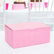 A pink bakery box with a lid on a table.