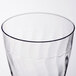 A close up of a clear Fineline plastic wine goblet with a wavy design.