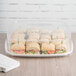 A clear Eco-Products Regalia compostable plastic lid on a tray of sandwiches with a napkin on the side.