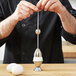 A person using a Matfer Bourgeat stainless steel egg topper on an egg.