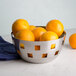 An American Metalcraft stainless steel checkered bowl filled with oranges on a table.