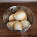 An American Metalcraft stainless steel checkered metal bowl filled with bread rolls.