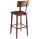 A Lancaster Table & Seating rustic industrial bar height chair with a wooden seat and metal legs.
