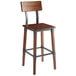 A Lancaster Table & Seating Rustic Industrial Bar Height Chair with a wooden seat and backrest on a metal frame.