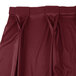 A burgundy Snap Drape table skirt with pleated detailing.