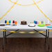 A table with a cake and cups on it with School Bus Yellow Streamer Paper decorating the table.