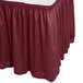 A burgundy table skirt with shirred pleats on a table with a white top.